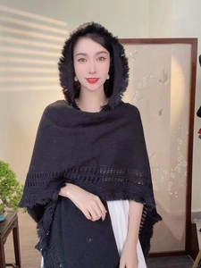Detail of black hooded knitted shawl with fringe tassels and hollow patterns