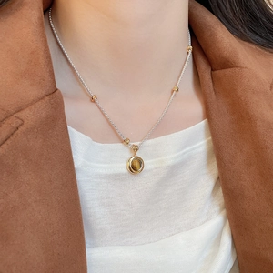 Detail of tiger eye pendant necklace on a model with vintage aesthetic style