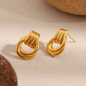 Close-up of 18K gold plated stainless steel intertwined hoop earrings on stones