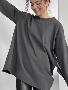 Primo piano del tessuto in cotone grigio scuro di una t-shirt a maniche lunghe ampia