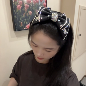 Detailed view of luxury black bow headband with sparkling rhinestones and sequins decoration