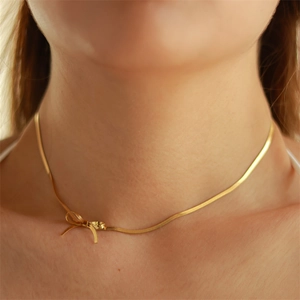 Elegant 18K gold plated titanium snake chain necklace with bow detail on female neck