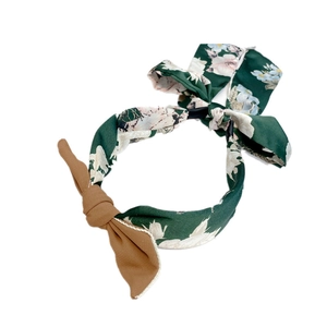 Detail of green floral fabric headband with a brown bow and braided texture design
