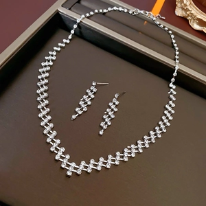 Close-up of geometric silver necklace and earring set with shimmering crystals