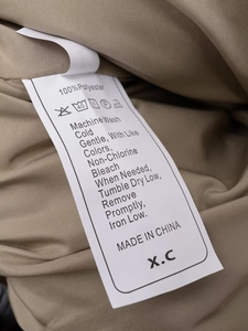 Detail view of the 100% polyester care label with clear washing instructions and icons