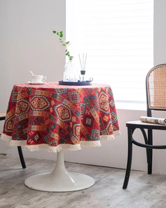 Macro detail of red ethnic jacquard tablecloth with white tassel edge on round table