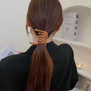Close-up of caramel faux leather hair tie wrapped around a ponytail with gold tips