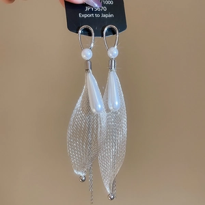 Close-up of pearl drop earrings with silver mesh fabric and elegant long tassels
