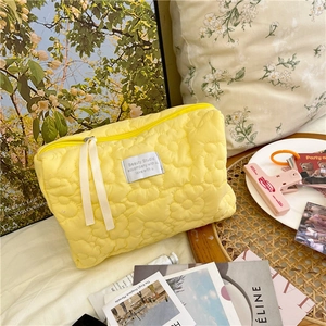 Detail of yellow quilted floral makeup bag with ribbon zipper and woven label