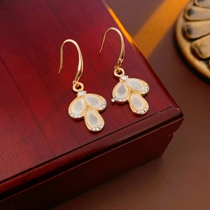 Detail of teardrop cat eye stone earrings with zircon petals on a dark wood box