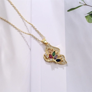 Close-up of golden butterfly pendant with colorful gemstones on a white fabric background