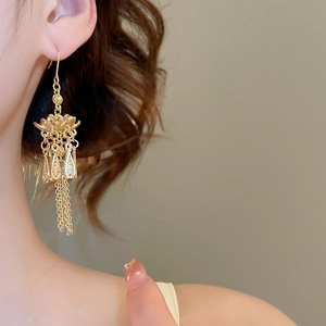 Detailansicht der goldenen Lotus-Ohrringe mit Quasten am Modell im Retro-Stil