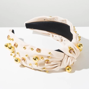 Close-up of beige knotted headband with gold beads and pink crystal rhinestones