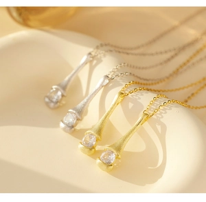 Detail of matte brushed silver and gold pendants with zircon stones on a chain