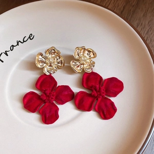 Close-up of vintage gold and red velvet flower earrings resting on a ceramic plate