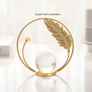 Modern gold crystal ball ornament with metal feather accents on stable round base