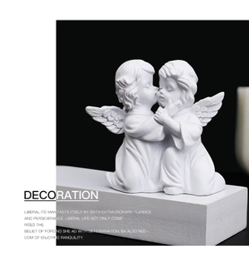 Artistic close-up of white resin angel figurines on pedestal with black background