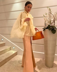 Detail of yellow tulle blouse with lantern sleeves paired with high-waist trousers