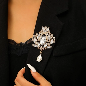 Detailed close-up of a vintage golden crown brooch with crystals on a black suit lapel