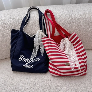 Detail of canvas tote bags with striped patterns and delicate white lace bow ornaments