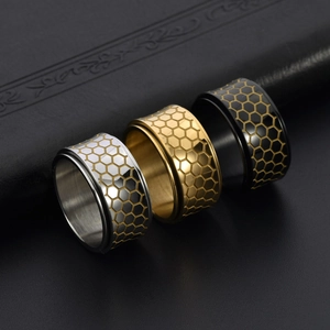 Detailed view of rotating honeycomb rings in gold, silver, and black stainless steel