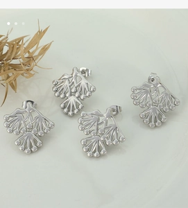 Detailed macro shot of four silver pine branch stud earrings in polished stainless steel