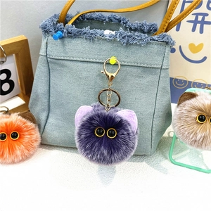 Dettaglio di simpatici portachiavi a forma di gatto in peluche su borsa di jeans