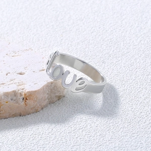 Detailed view of silver stainless steel ring with hollowed love letter design on white stone