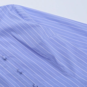 Dettaglio macro di strisce blu verticali e bottoni rivestiti su camicia in tessuto
