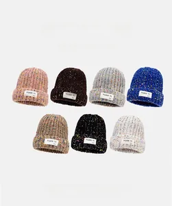 Flat lay of knit beanies in multiple colors like pink, khaki and navy blue with logo labels