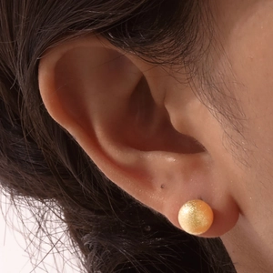 Minimalist gold ball stud earrings for women with a textured shimmer finish on ears
