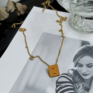 Detail shot of a golden square pendant with letter Z resting on a lifestyle magazine