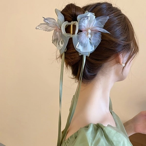 Detail of organza butterfly hair claw with pearls and long flowing ribbons on model