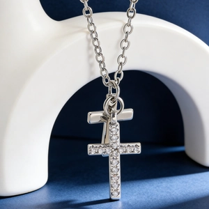 Macro shot of silver crown cross necklace featuring clear zircon stones and polished finish
