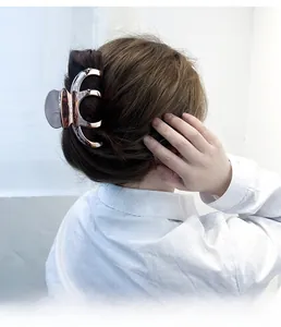 Detail of rose gold metal shark hair claw clip holding hair in a modern bun style