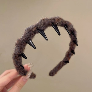 Detailed texture of dark brown acrylic knitted wave headband with internal black comb teeth