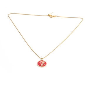 Detailed macro of gold-plated chain and red enamel flower pendant with gemstones