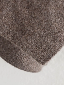 Macro detail of thick brown wool fabric showing fiber texture and premium quality material