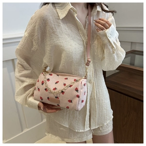 Detail of pink strawberry cylinder bag with corduroy texture and gold chain strap