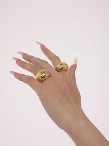 Detail of 18k gold plated wide band ring with embossed heart texture on finger