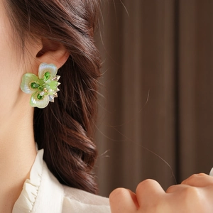 Gros plan de boucles d'oreilles fleurs en perles et cristaux verts sur le modèle
