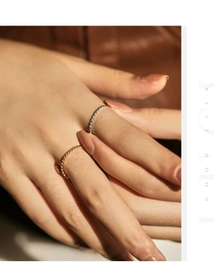 Detail of twisted rope design rings in gold and silver finish on a female hand