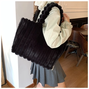 Detail of black plush tote bag with unique spherical beaded strap worn by a model