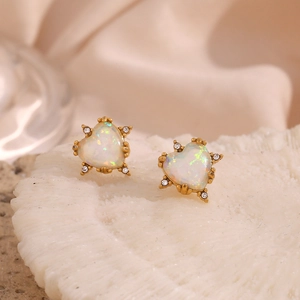 Macro view of gold-plated heart stud earrings featuring white opal and tiny clear crystals
