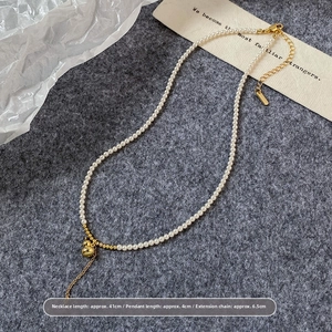 Détail du collier de perles avec pendentif gourde dorée et fermoir mousqueton ajustable