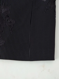 Détail du tissu noir à rayures avec une broderie florale exquise de sequins brillants
