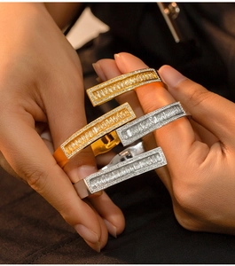 Detail of stacked titanium steel bangles with emerald-cut diamonds and pave-set accents