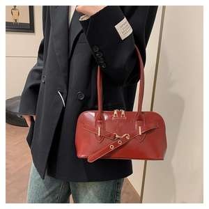 Detail showing red glossy patent leather shoulder bag with decorative buckle accent