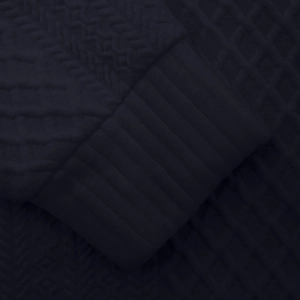 Detailaufnahme des dunkelblauen Strickpullovers mit Rautenmuster und gerippten Bündchen