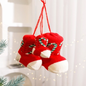 Three red knitted Christmas stocking boot ornaments with candy cane patterns on a cozy background